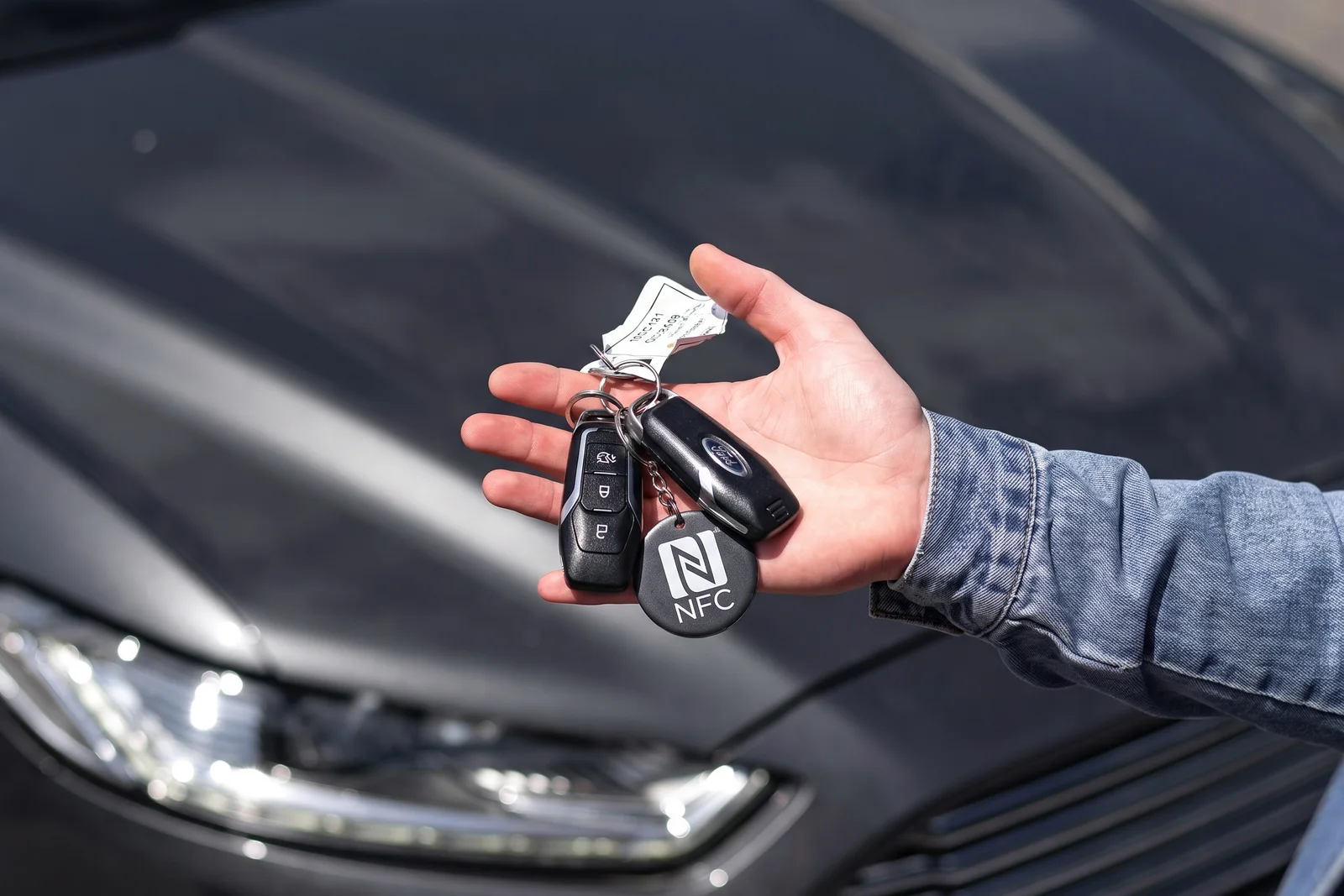 Rental car keys with an NFC tap tag, in front of the car